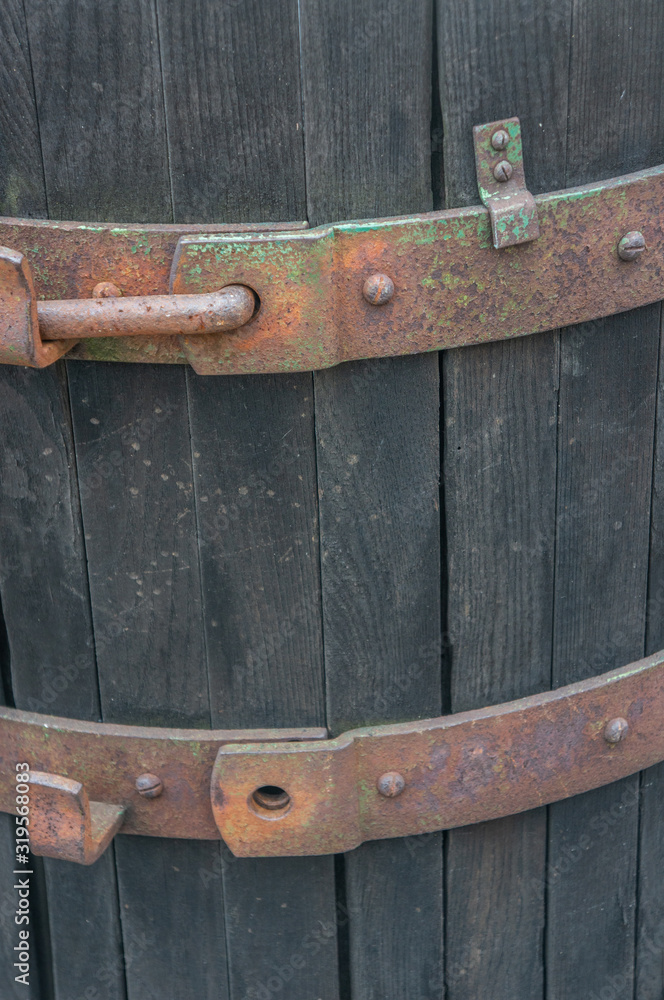 Closeup of rusted brass details with peeling green paint on a vintage rustic wine casket. Dark cold brown wooden barrel shot in daylight during winter season.
