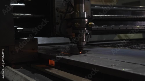 automated laser cutting of metal with sparks in a poorly lit room against the macro