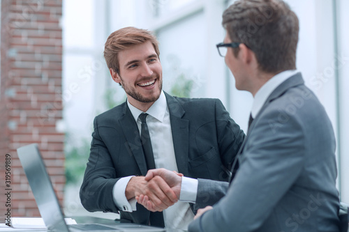business colleagues shaking hands while sitting at the Desk