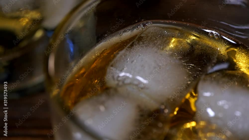 Ice cubes melts in a glass of malt whiskey Ice cubes melts in a glass of malt whiskey