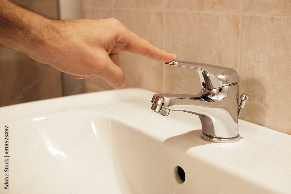 a person closes the water tap of the bathroom a person closes the water tap of the bathroom