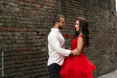 Beautiful romantic couple. Attractive young woman in red dress and crown with handsome man in white shirt are in love. Happy Saint Valentine's Day. Pregnant and wedding concept.