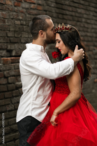 Beautiful romantic couple kiss closeup. Attractive young woman in red dress and crown with handsome man in white shirt are in love. Happy Saint Valentine's Day. Pregnant and wedding concept.