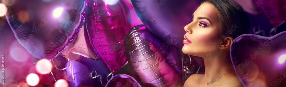 Fototapeta Uroda moda model dziewczyna kreatywnych sztuki makijażu, na tle balonów powietrza fioletowy, różowy i fioletowy. Twarz kobiety Makijaż z klejnotami, róż ze złotymi ustami, fioletowe cienie do powiek. Szeroki ekran