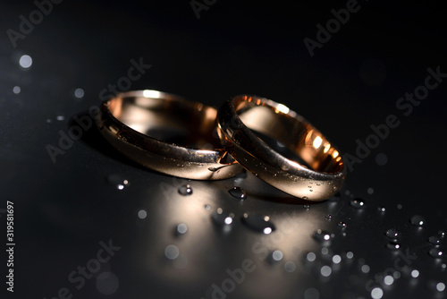 Wedding rings black background white rose drops