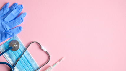 Medical equipment and tools on pink background. Top view stethoscope, surgical mask, medical gloves, syringe on pink background with copy space. Healthcare and medicine concept. Medical banner design