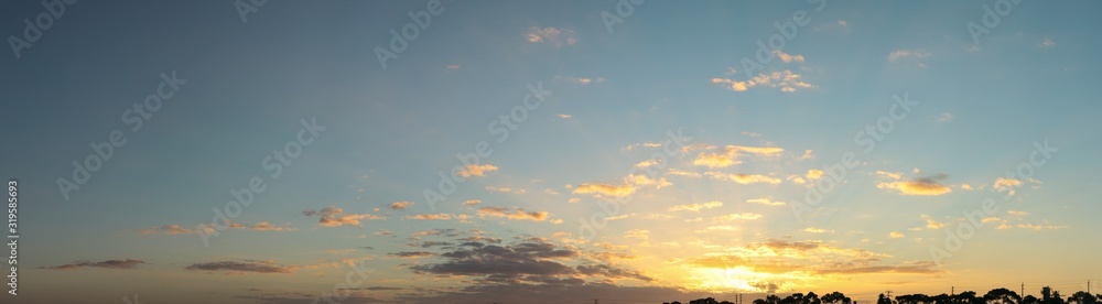 Obraz premium panoramic landscape showing the fiery burning colors of the sun setting in the clouds after a hot summers day in Australia