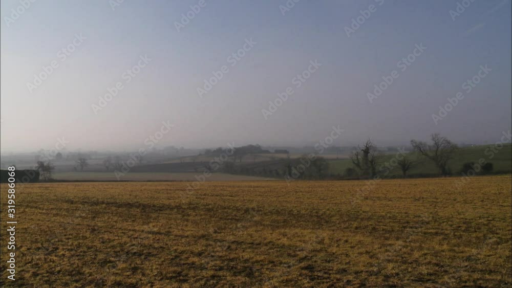 Wide low angle daytime still shot of a remote dry cultivated farmland with misty horizon, countryside scene Wide low angle daytime still shot of a remote dry cultivated farmland with misty horizon, countryside scene
