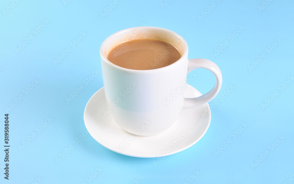 White cup of creamy coffee isolated on blue background.