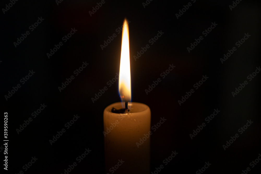 Candle flame in total darkness. A wax candle shines in flame. The wick burns. Church candle for prayer. Orthodox rite. Candle flame in total darkness. A wax candle shines in flame. The wick burns. Church candle for prayer. Orthodox rite.