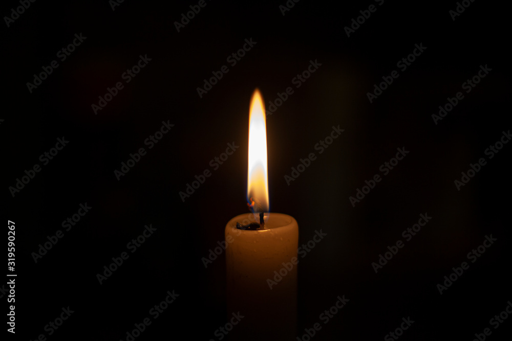 Candle flame in total darkness. A wax candle shines in flame. The wick burns. Church candle for prayer. Orthodox rite. Candle flame in total darkness. A wax candle shines in flame. The wick burns. Church candle for prayer. Orthodox rite.