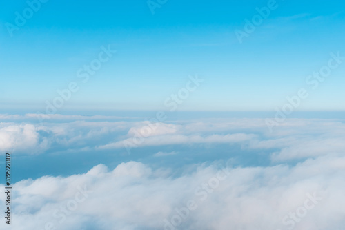 Airplane window view above beautiful white cloud summer blue sky and sun light abstract nature.