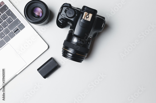 Photographer's workplace on a white background. Modern laptop, digital camera, lens, battery, smartphone. Minimalism. Top view. Copy space. Equipment for the photographer. The concept of freelancing