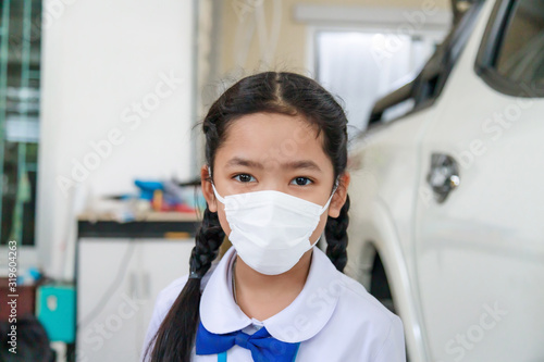Little Asian girl in Thai student uniform wearing virus protective flu mask, Health care concept, select focus shallow depth of field