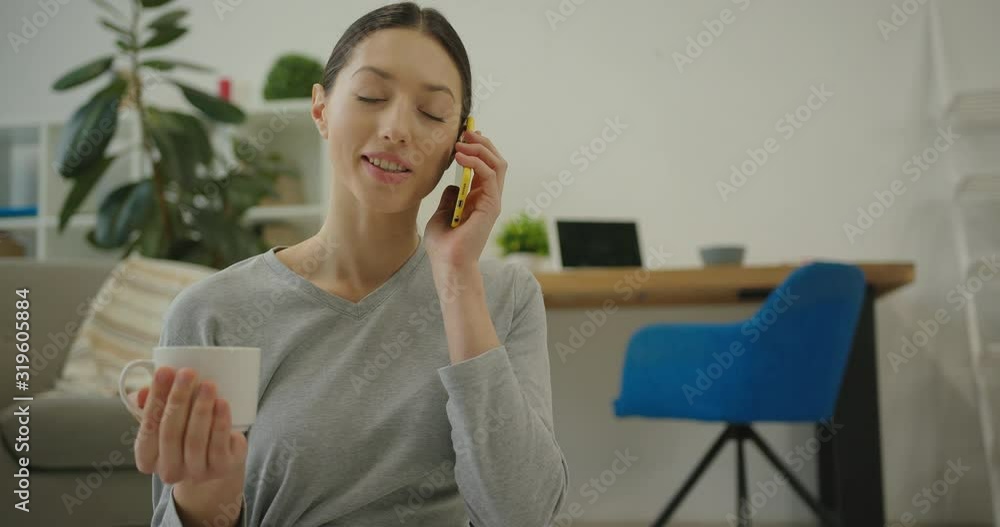 athletic young woman talking on smartphone and laughing with a cup of tea in her hand athletic young woman talking on smartphone and laughing with a cup of tea in her hand