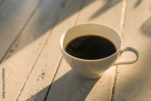A cup of black coffee putting on the table as shadow and light.