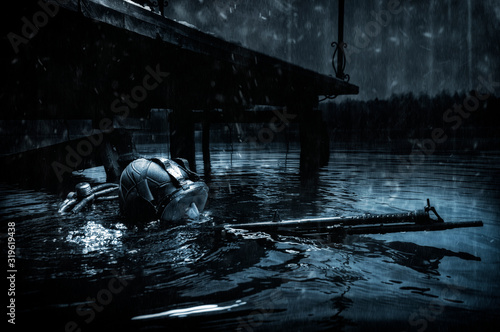 Military diver emerges from under the water and takes aim from the machine gun. The concept of special military operations, wars, political instability.