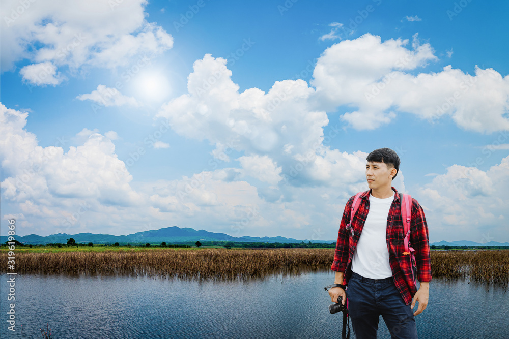 Young traveler man staying on the lake in summer time.