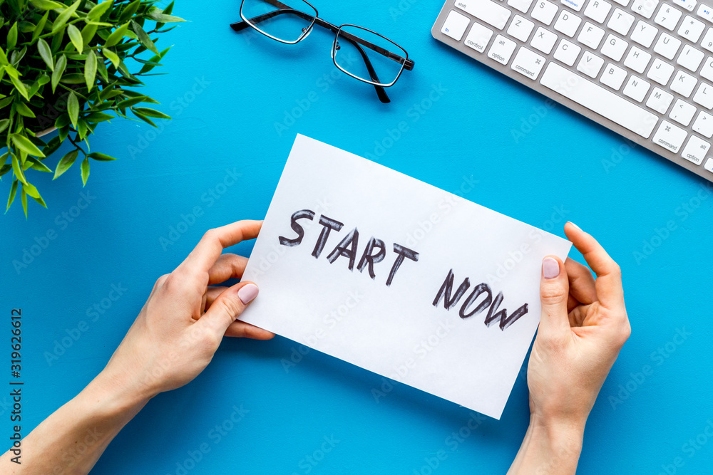 Start now. Motivative text on blue office desk top-down Start now. Motivative text on blue office desk top-down