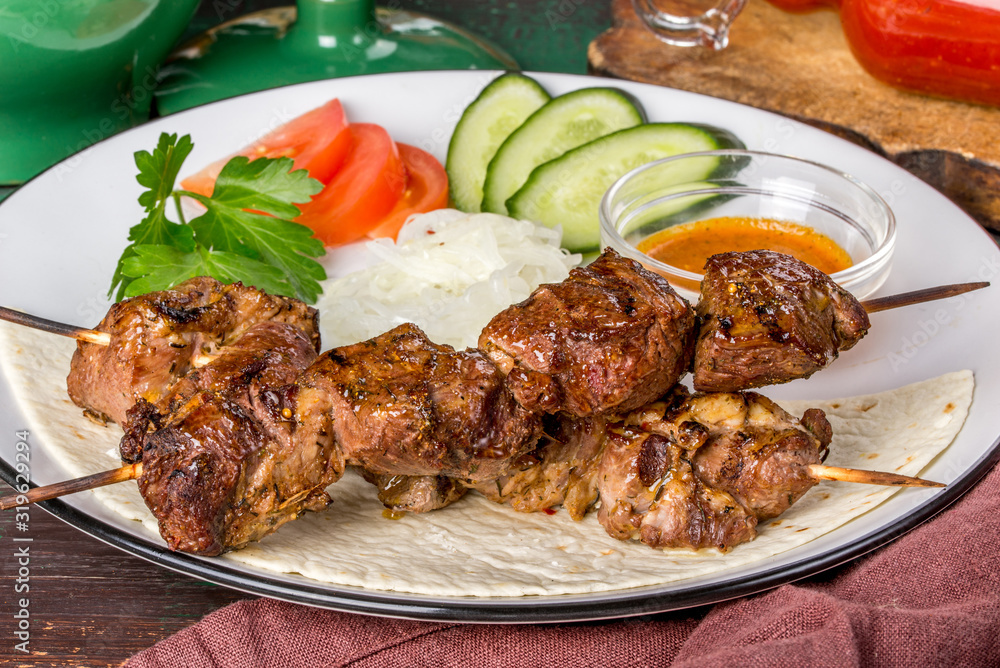 Lamb shish kebab with vegetables on a white plate