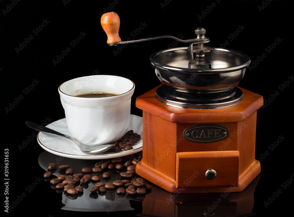 coffee grinder with a Cup of coffee and coffee beans scattered between them on a black background coffee grinder with a Cup of coffee and coffee beans scattered between them on a black background