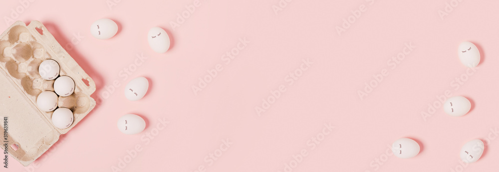 Happy Easter web banner. White eggs with painted eyes in paper packaging on a pink background. Flat lay, top view, copy space.