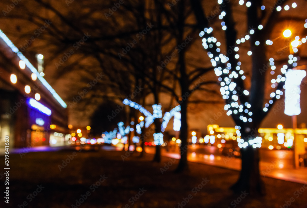Street city lights out of focus at night, bokeh, decoration on the trees