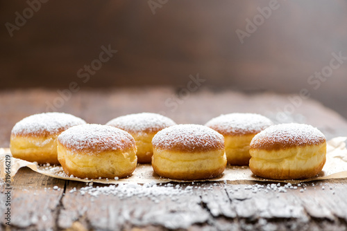 Close-up of donuts (Berlin pancakes) dusted with powdered sugar served on a rustic wooden table