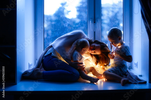mother with two children at window, evening mood