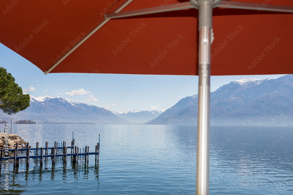 Alpine Lake with Snow-capped Mountain Under a Parasol in Ticino, Switzerland.