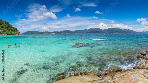 sea view panorama of arch rocks and tourists in blue-green sea with blue sky background  Ko Rokroy  Tarutao National Park  Satun  southern of Thailand.