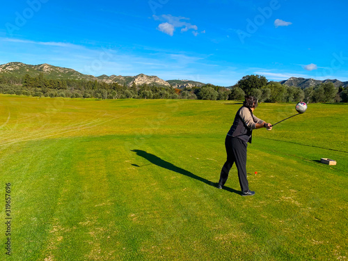 Golfer Teeing Off with Driver and with Mountain View in France.