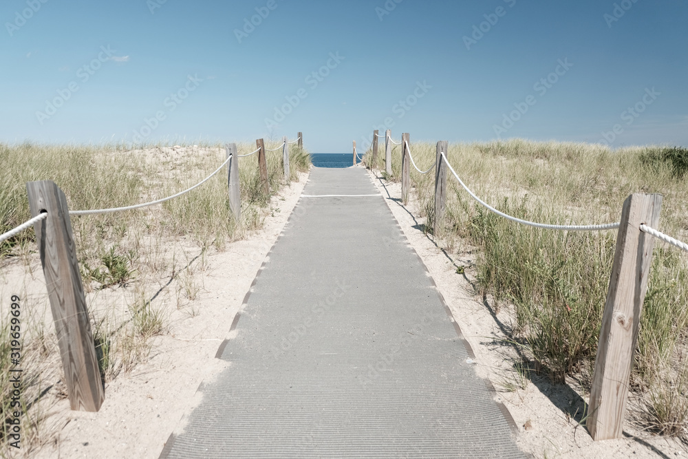 Entrance to endless white and sandy beach on Cape Cod, Massachusetts, USA. You were offered relaxing walks between reed grass and the Atlantic Ocean on beautiful summer days.