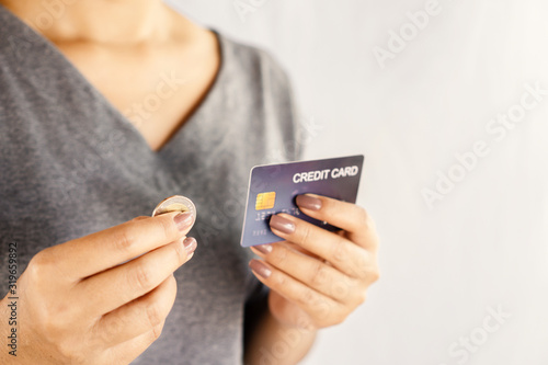 shopaholic Asian woman over spending on credit card hand holding one coin 