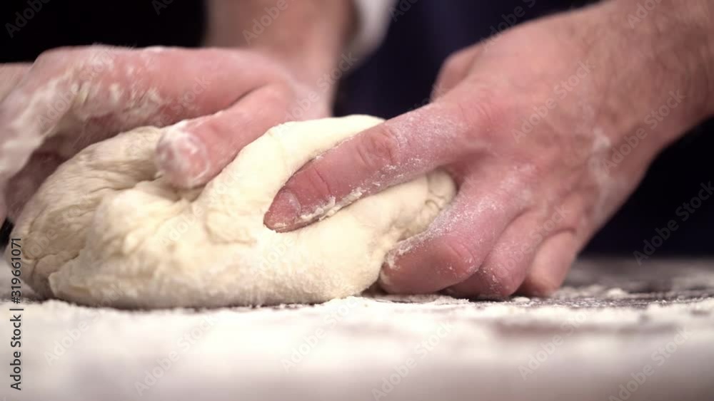 Baker kneading dough in flour on table Baker kneading dough in flour on table