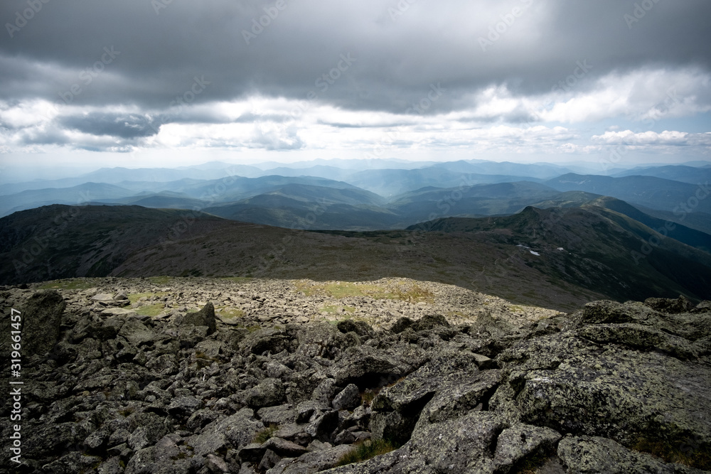 Panoramic view on the peak of Mount Washington, New Hampshire (USA). The shot covers the rough landscape, dark clouds and an infinite view offered on mountains`peak.