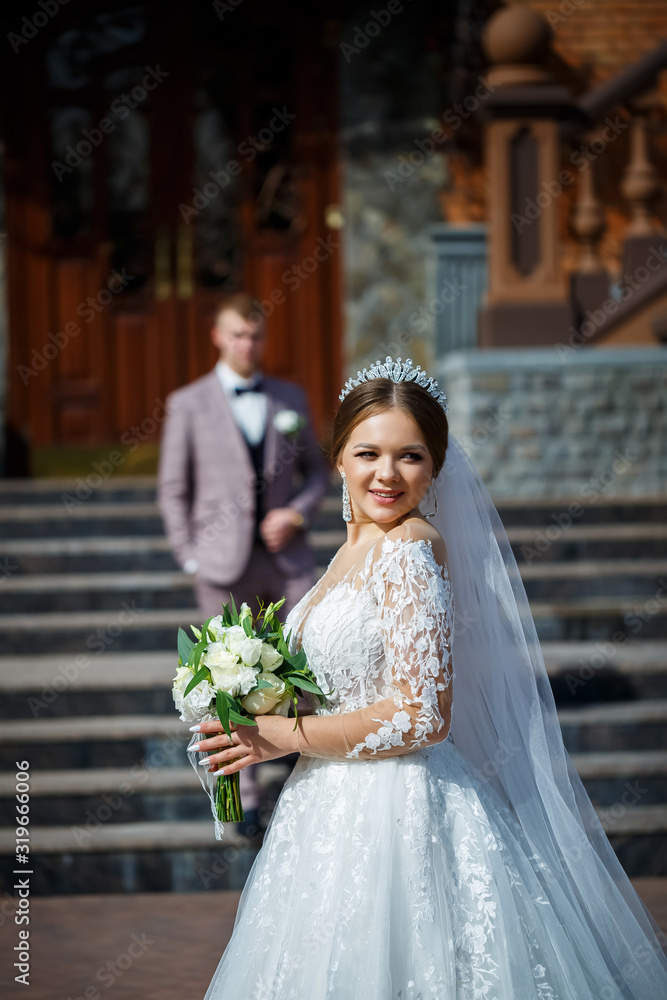 The bride in a white wedding dress and groom in a suit on the background of a brick building with large steps The bride in a white wedding dress and groom in a suit on the background of a brick building with large steps