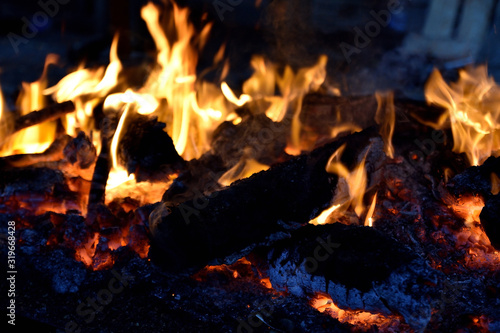logs of wood with flames and burning embers in the fireplace