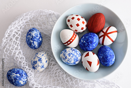 abstract Easter eggs with red geometric patterns and in the color of the year-classic blue in blue plate on white mesh eco bag