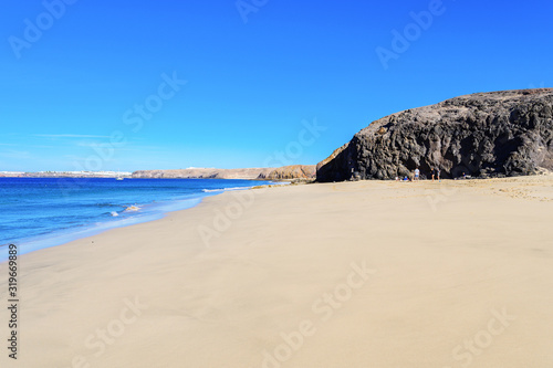 View of beautiful Papagayo beach near town named Playa Blanca, Lanzarote, Canary Islands. View of blue sea, yellow sand, selective focus