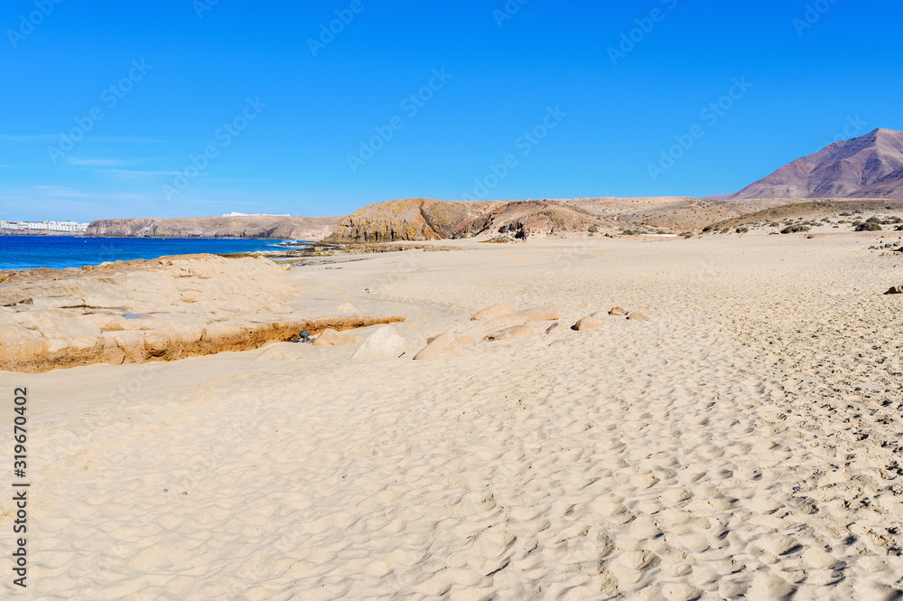View of beautiful Papagayo beach near town named Playa Blanca, Lanzarote, Canary Islands. View of blue sea, yellow sand, selective focus