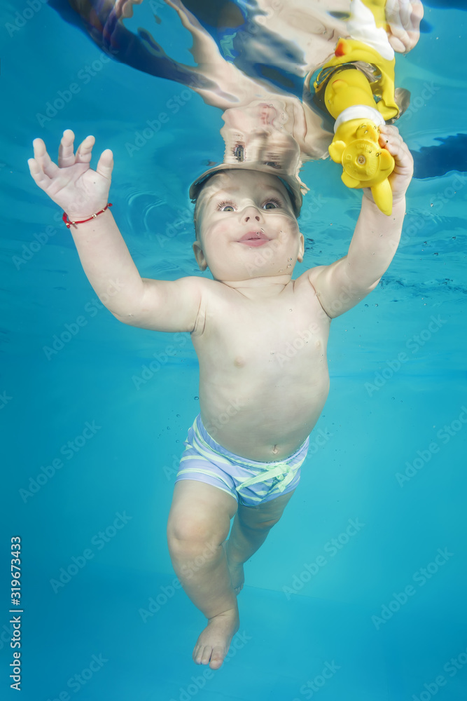 Little boy play with toy underwater in a swimming pool