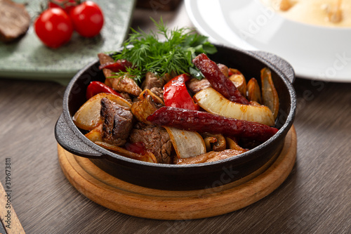 Home-made Pork Sausages in rustic pan. Sausages cooking in frying pan. Close up of fried sausages in frying pan over wooden background