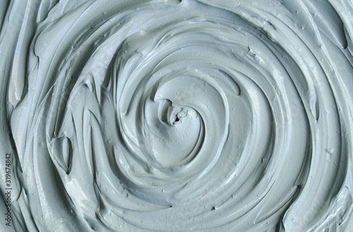 Gray bentonite facial clay (mask, face cream, body wrap) texture close up, selective focus. Abstract background with circle brush strokes.