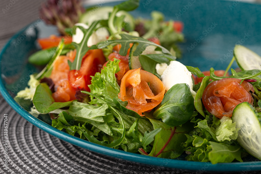 Delicious fresh salad. Salad with salmon, mozzarella cheese, cherry tomatoes, arugula, olive oil. Fresh salmon salad with mozzarella and vegetables. Close up view on Salad. Healthy, diet tasty summer Delicious fresh salad. Salad with salmon, mozzarella cheese, cherry tomatoes, arugula, olive oil. Fresh salmon salad with mozzarella and vegetables. Close up view on Salad. Healthy, diet tasty summer