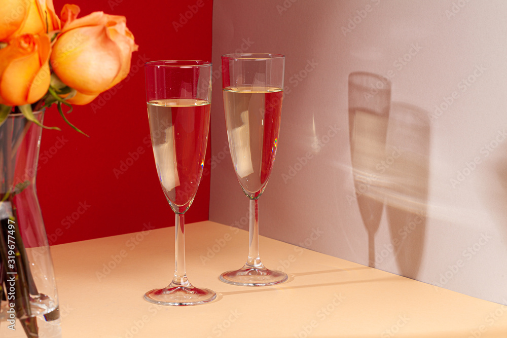 Close up photo of champagne glasses with roses in a vase