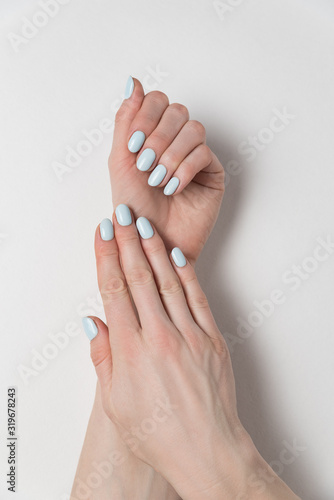 Female hands with delicate blue manicure. Gel Polish. White background. Verrical frame