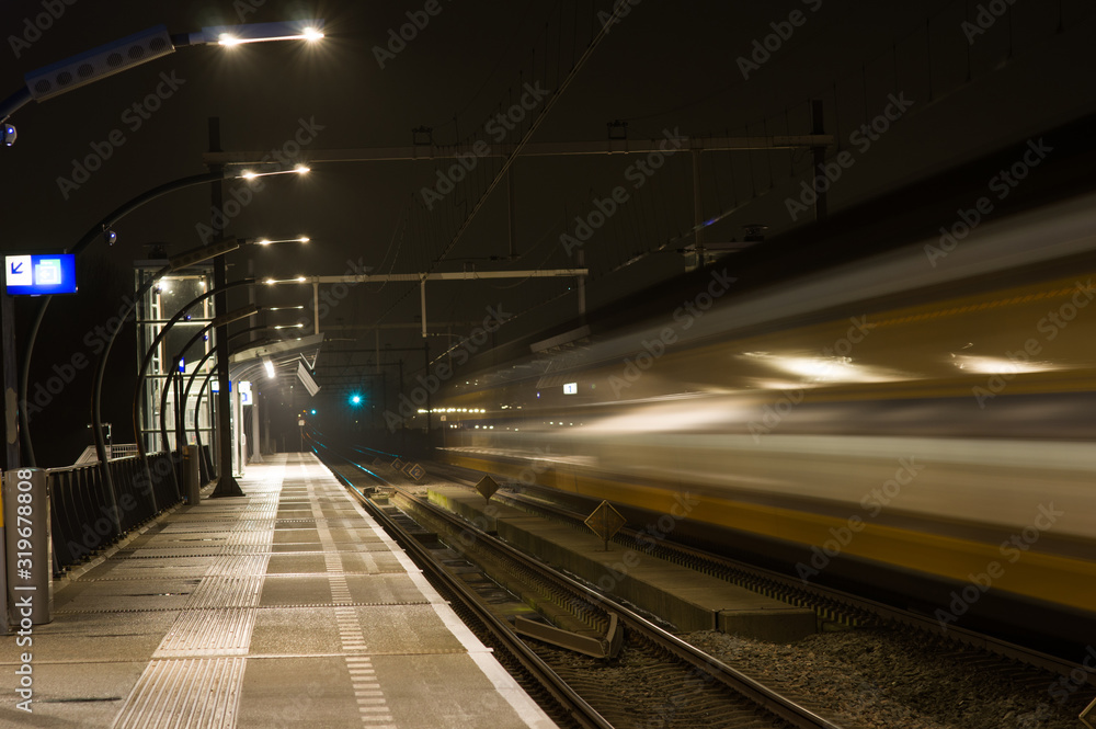 Blurred train by motion at night at station Arnhem south, Netherlands