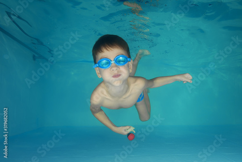 A boy in goggles plays underwater in a swimming pool