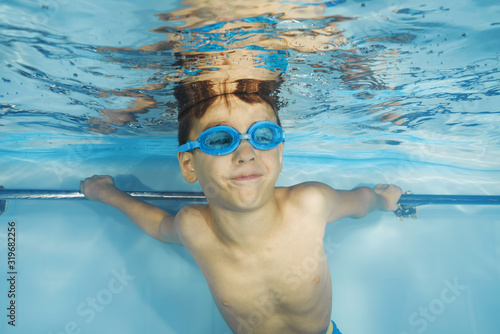 A boy in goggles plays underwater in a swimming pool